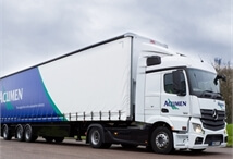 side view of an Acumen Logistics distribution lorry driving down a country side road